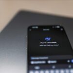 Close-up of a smartphone with AI assistant interface on screen over a laptop.