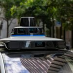 Detailed view of sensors atop an autonomous car, showcasing advanced technology in an urban setting.