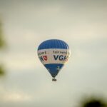 A blue hot air balloon with text flying in a clear sky, creating a serene travel scene.