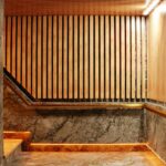 Elegant staircase with wooden panels and marble walls, illuminated by warm lighting.