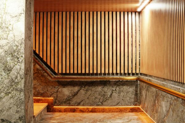 Elegant staircase with wooden panels and marble walls, illuminated by warm lighting.