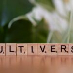 Wooden Scrabble tiles spelling multiverse against a blurred leafy background.