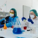 Two female scientists examining samples in a bright, modern laboratory setting.