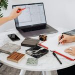 Two designers collaborate on a project with laptop and material samples on a marble table.