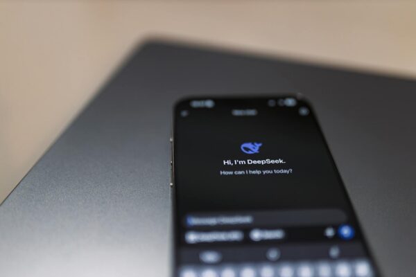 Close-up of a smartphone with AI assistant interface on screen over a laptop.