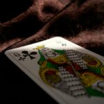Close-up of a Queen of Clubs playing card on a dark velvet fabric, highlighting themes of gambling and chance.