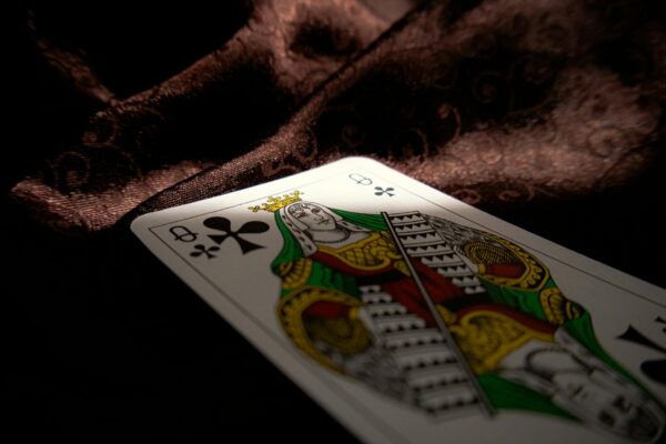 Close-up of a Queen of Clubs playing card on a dark velvet fabric, highlighting themes of gambling and chance.