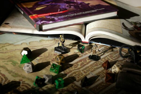 Close-up of tabletop RPG setup with books, dice, and figurines on a map.