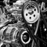 Close-up of a shiny car engine showing polished metal parts and gears in black and white.