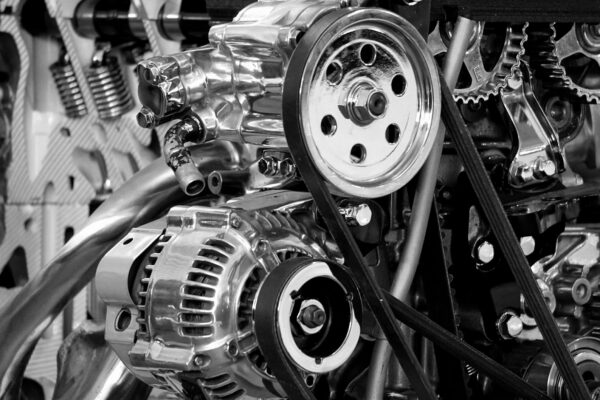 Close-up of a shiny car engine showing polished metal parts and gears in black and white.
